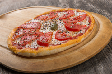 Pizza margarita with cheese and tomato isolated on rustic wooden table