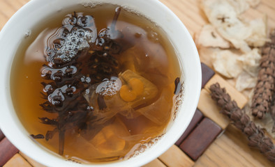 bowl of Chinese herbal tea with raw herbal nearby