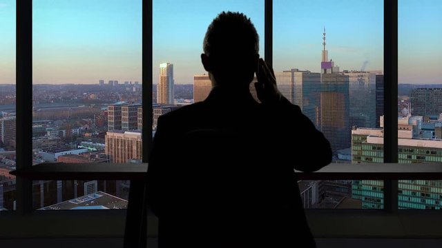 business man sits into modern office celebrating good news skycrapers background