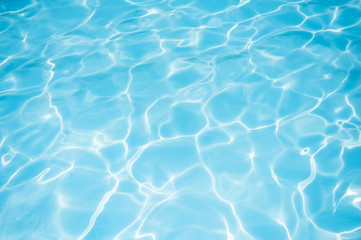 Fototapeta na wymiar Ripple blue water surface with sun reflection in swimming pool