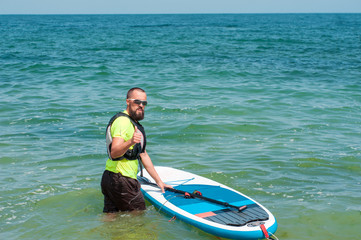 jolly man with a paddle floats on stand up paddle board on the s