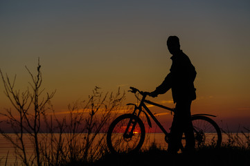 Fototapeta na wymiar Dark silhouette of a cyclist on the beach