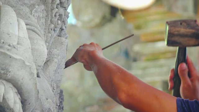 Asian sculptor, painstakingly chipping away at fine, intricate details of a stone work of art, using a traditional wooden hammer and simple chisel. Video UltraHD
