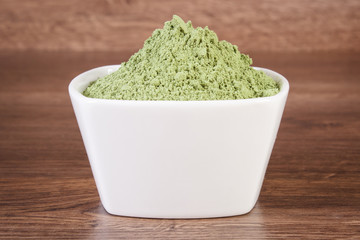 Heap of young powder barley in bowl on wooden background, body detox