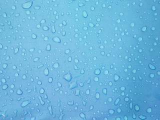 Fototapeta na wymiar water drops on blue waterproof fabric