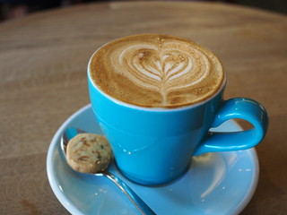 Hot piccolo latte with a small biscuit