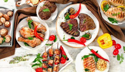 Assorted grilled meats and vegetables on  wooden background.
