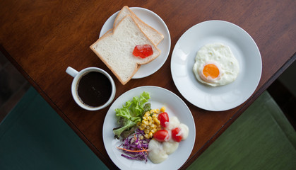 breakfast with cup of black coffee, eggs and croissants on balcony