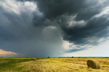 Dramatic scenery with field, storm clouds and haystacks
