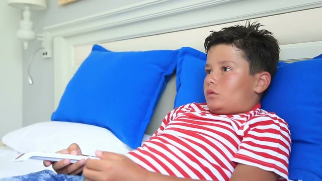 Child lying on a bed and watching television
