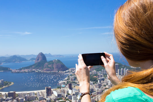 girl tourist takes a picture of Rio landscape with smartphone