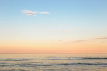 Obraz premium Still blue sea water under colorful evening cloudy sky