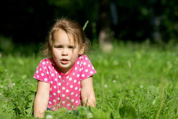 Naklejka na ściany i meble Девочка в парке лежит на траве, в платье в горошек