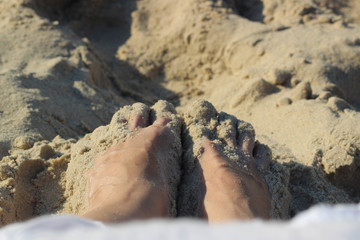 Female feet on the beach, on the sand background