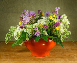 Still life. Bouquet of meadow flowers in orange pots