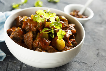 Goulash, served in white bowl with fresh herbs