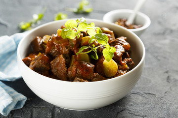 Goulash, served in white bowl with fresh herbs