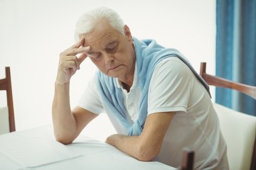 Sad senior man sitting at table