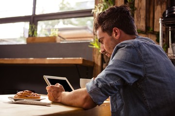 Man drinking coffee and using tablet