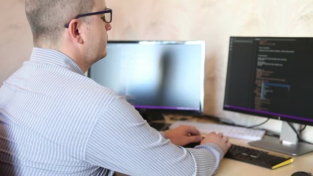 programmer man wearily third person sitting at a computer