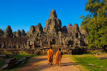 The monks in the ancient stone faces of Bayon temple - obrazy, fototapety, plakaty