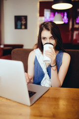 outdoor portrait of a young girl she works as a freelancer in a cafe drinking a delicious hot Cup of coffee from text send mail loads the photo instagram freelancer