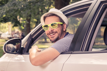 Naklejka premium Portrait of young driver wearing sunglasses in driver’s seat. Vacation and travel concepts.