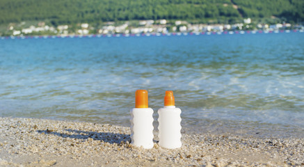 two bottles of sunscreen with shell and sunglasses on the beach.summer sunbath - suntan oil