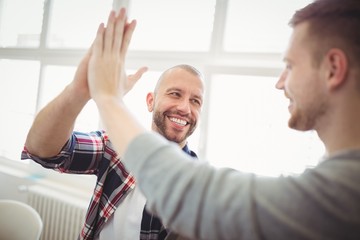 Male coworkers giving high-five - Powered by Adobe