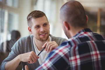 Young businessman discussing with colleague in office