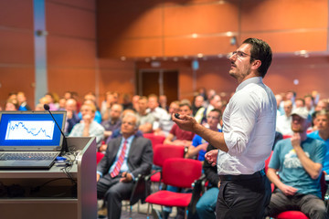 Speaker giving a talk on corporate Business Conference. Audience at the conference hall. Business...