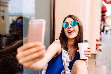 Attractive woman taking photo with take-out coffee on her phone