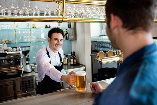 Bartender serving beer to male customer 
