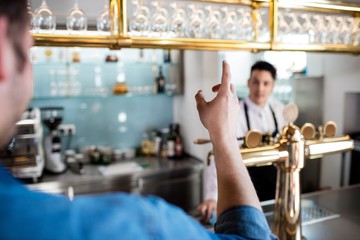 Man gesturing while talking with bartender