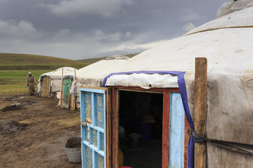 Gers at a Summer nomad camp under dark skies with nomadic man wearing deel, Khujirt, Uvurkhangai (Ovorkhangai), Central Mongolia