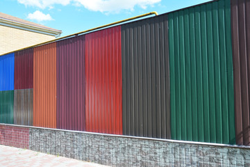 Stacks of various colorful metal fence panels and metal roof sheets for sale. Building and construction materials, colored steel roof tiles for sale.