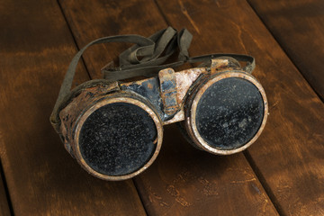Old rusty steampunk goggles on wooden desk