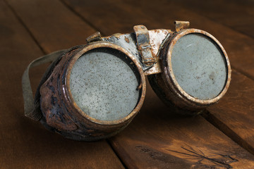 Old rusty steampunk goggles on wooden desk