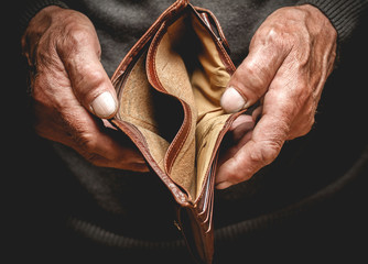 Empty wallet in the hands of an elderly man. Poverty in retirement concept - obrazy, fototapety, plakaty
