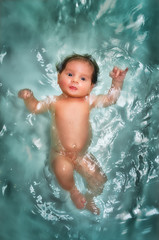 Pretty newborn baby swimming in the water