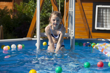 Happy little Girl in bikini swimming pool