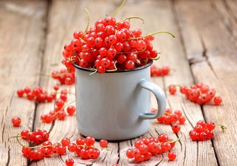 Fresh organic red currants in a cup on the old wooden table.