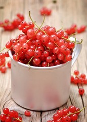 Fresh organic red currants in a cup on the old wooden table.