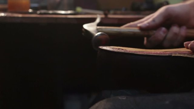 Shoemaker sews shoes. Hammering shoe leather