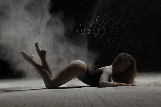 Sexy woman lying on floor and dancing with flour