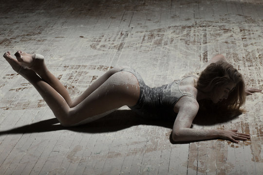 Sexy woman lying on floor and dancing with flour