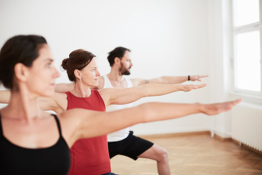 People in exercise studio arms open in yoga position