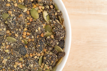 Chia cranberry and pumpkin seeds breakfast cereal in bowl atop a wood table.