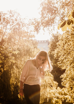 Woman Using Mobile Phone In Park, Copenhagen, Denmark