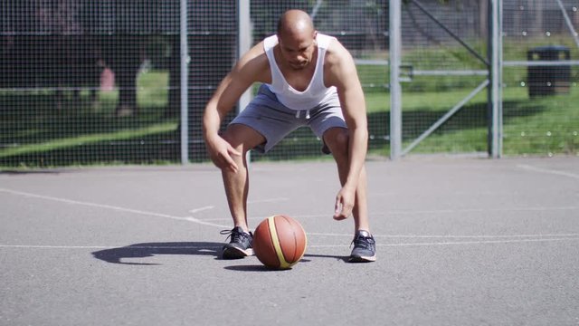 4K Man runs up to a basketball and starts dribbling with skill, in slow motion